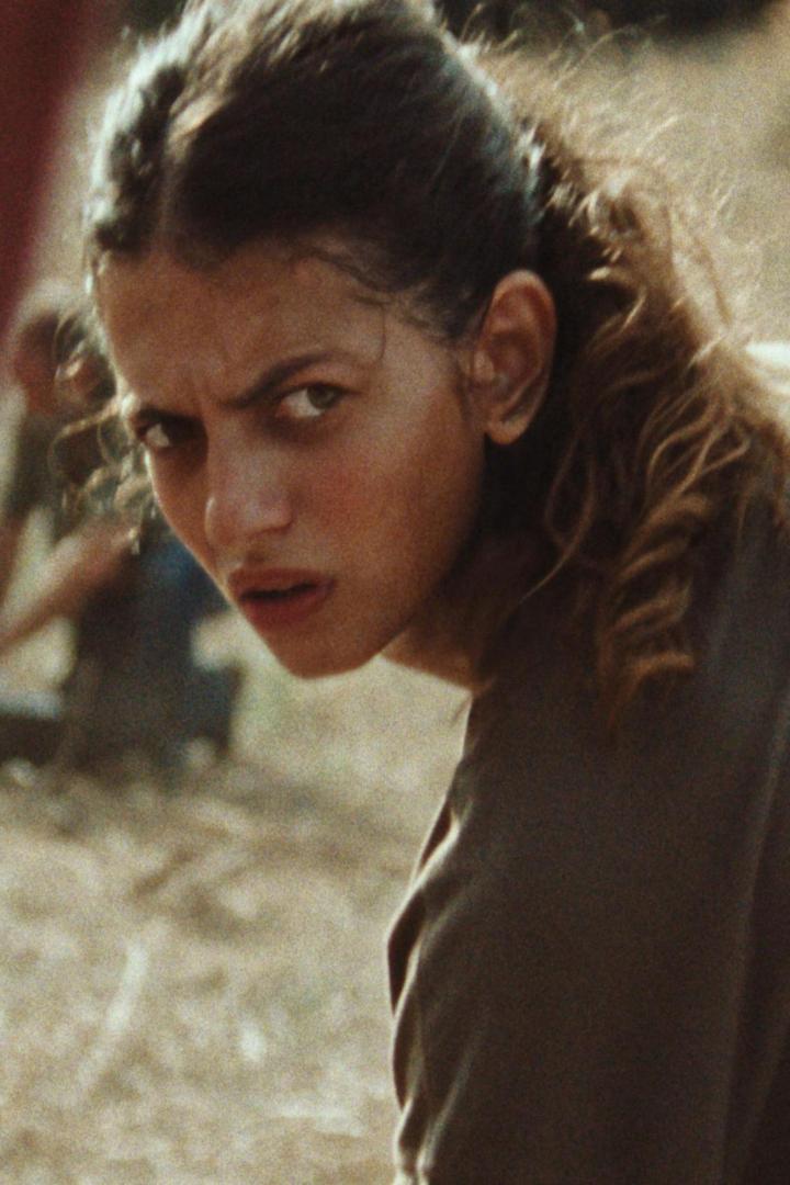 Eine junge Frau blickt mit ernstem Blick über ihre Schulter.