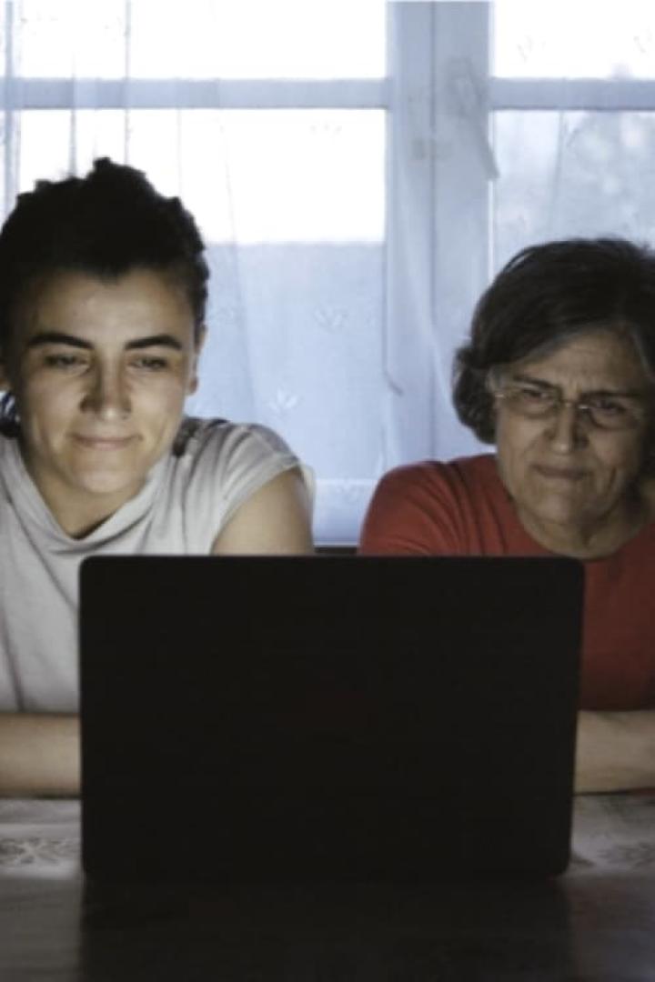 Eine junge und eine ältere Frau sitzen vor einem Laptop.