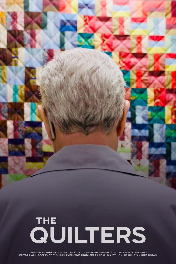 Ein Mann betrachtet von hinten ein farbenfrohes Patchwork-Muster, das an eine Steppdecke erinnert; Filmposter „The Quilters“.