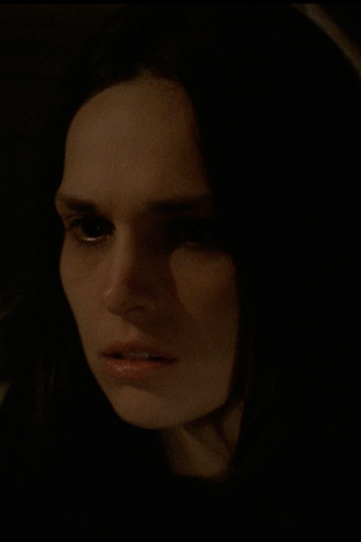 Nahaufnahme einer Frau im Dunkeln mit ernstem Gesichtsausdruck.