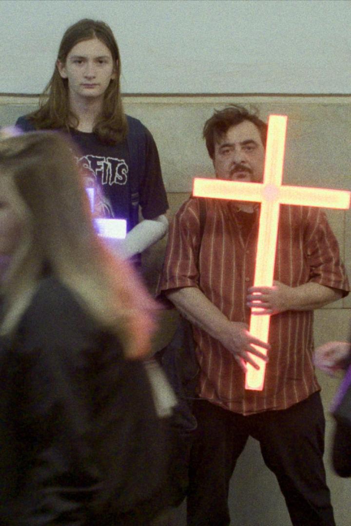 Ein Mann hält ein leuchtendes Kreuz in den Händen.