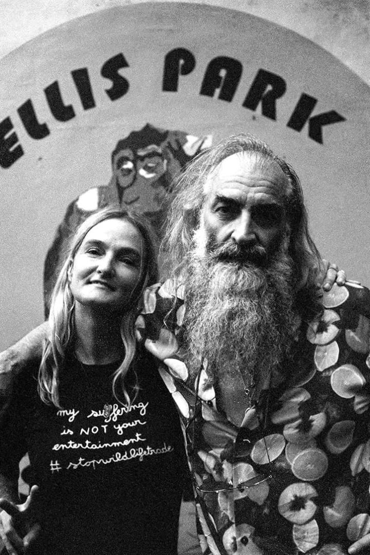 Ein Schwarzweißfoto von zwei Personen vor einem Schild mit der Aufschrift „Ellis Park“ und einem Affen.