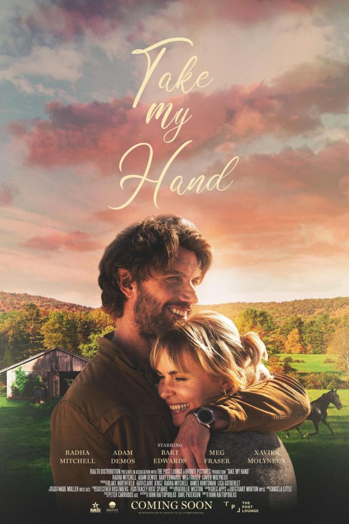 Das Filmplakat für „Take my Hand“ zeigt Radha Mitchell und Adam Demos in einer Umarmung vor ländlicher Kulisse.