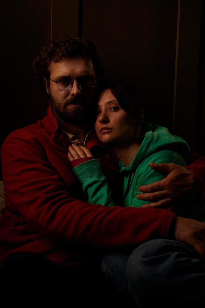 Ein Mann mit Brille umarmt eine Frau mit grünem Kapuzenpullover.