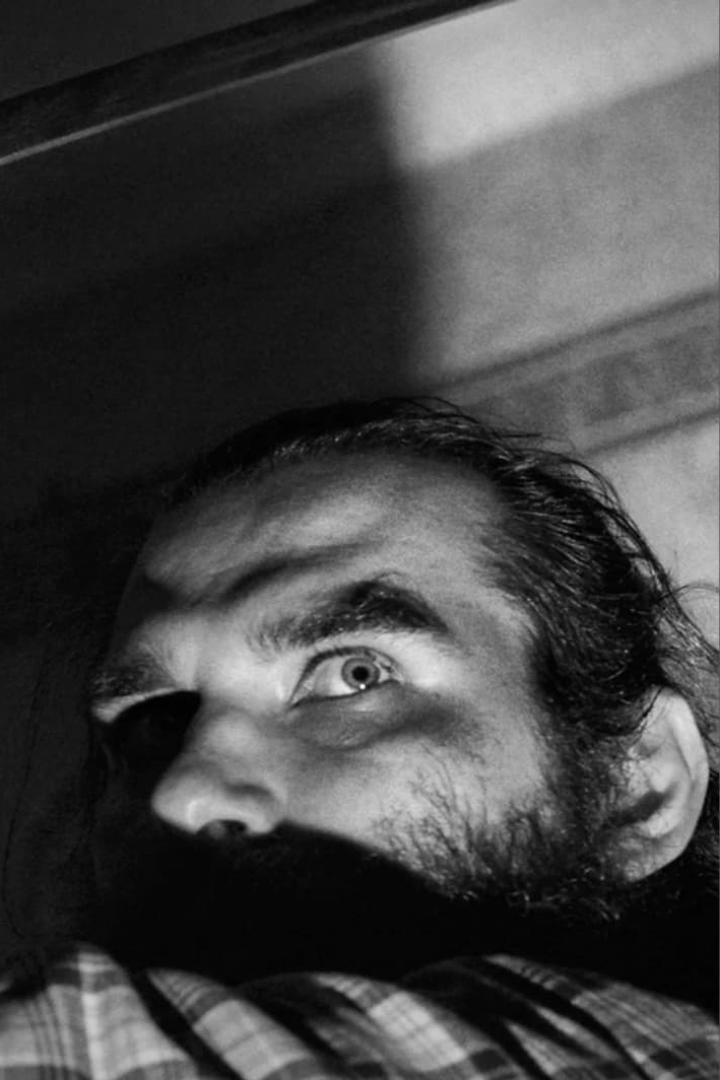 Ein Mann mit Bart blickt in einem Schwarzweißfoto nach oben.