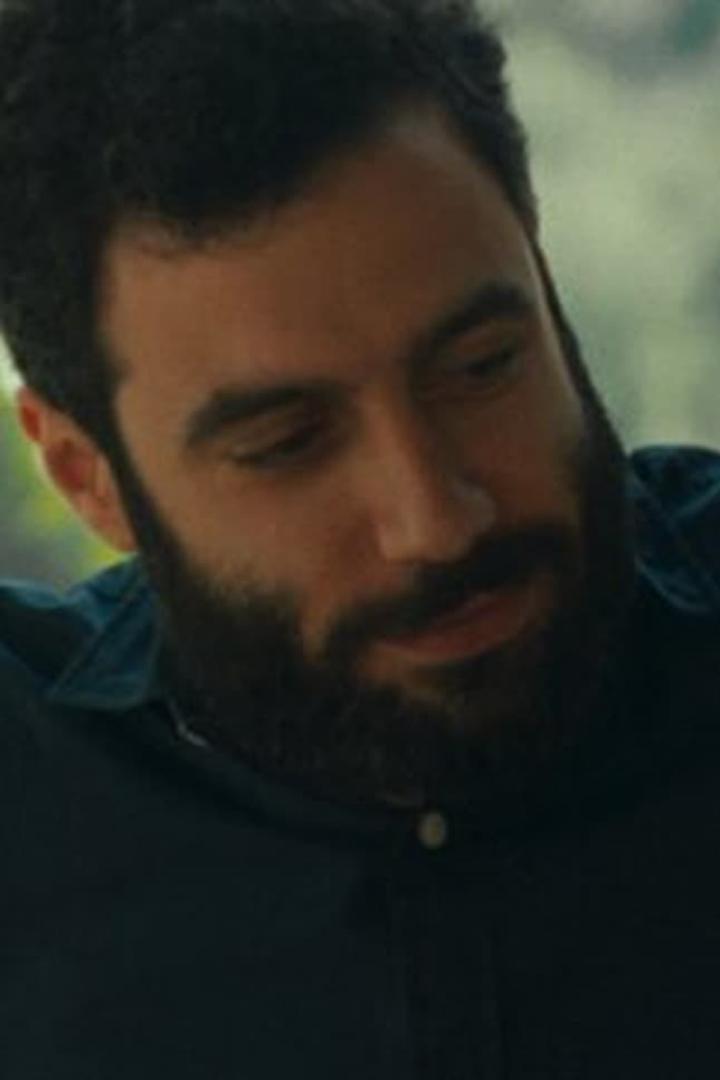 Ein Mann mit Bart und dunklem Haar schaut nach unten.