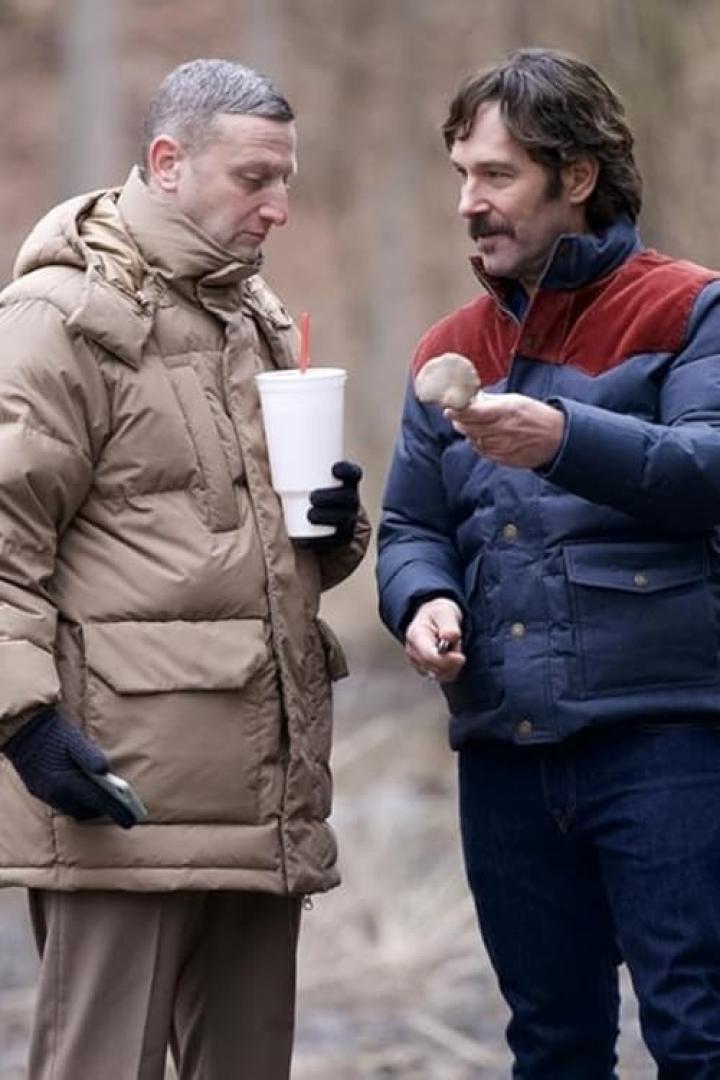 Zwei Männer stehen draußen, einer hält einen Pilz, der andere einen Becher mit Strohhalm.