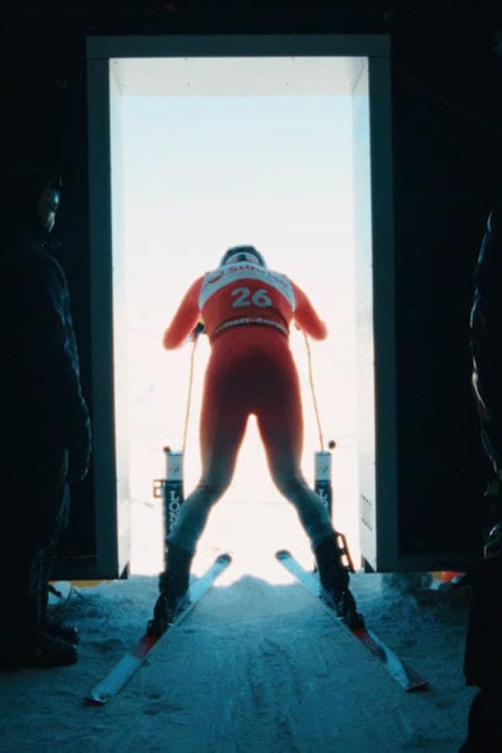 Ein Skirennläufer mit der Nummer 26 steht am Start und blickt auf die Piste.