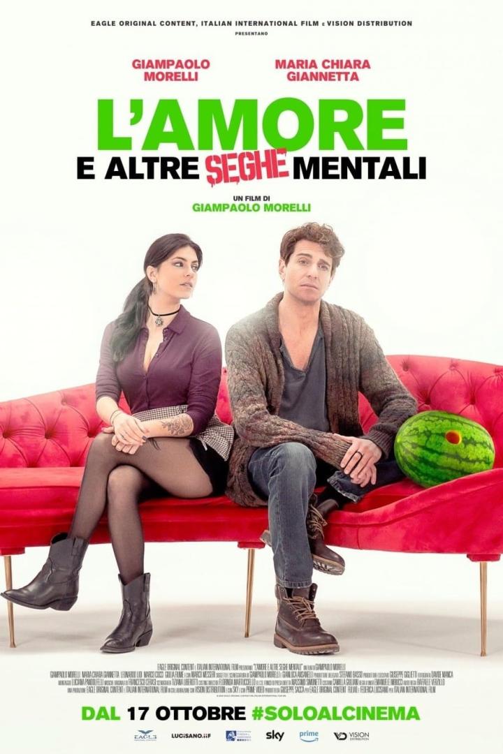 Das Filmplakat für „L'amore e altre seghe mentali“ zeigt Giampaolo Morelli und Maria Chiara Giannetta auf einem roten Sofa.