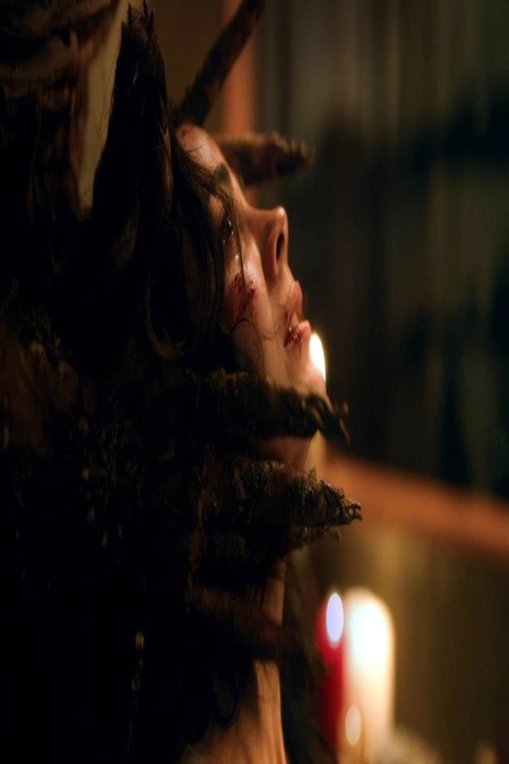 Eine verletzte Frau wird von dunklen, moosbewachsenen Händen gehalten.