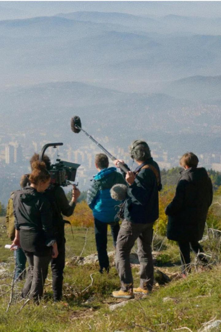 Ein Filmteam dreht eine Szene mit Blick auf eine Stadt in der Ferne.
