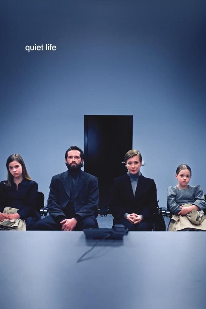 Eine Familie sitzt vor einer blauen Wand, darüber der Titel „quiet life“.