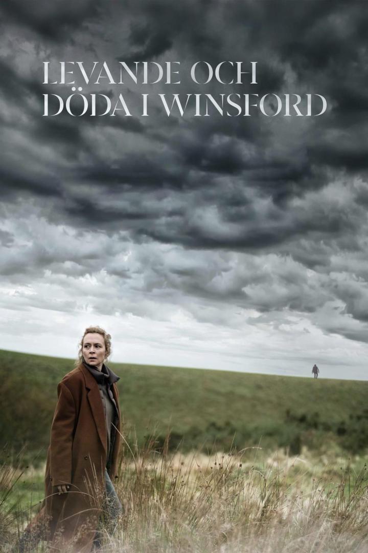 Eine Frau steht auf einem Feld unter einem dramatischen Himmel; im Hintergrund eine weitere Person.