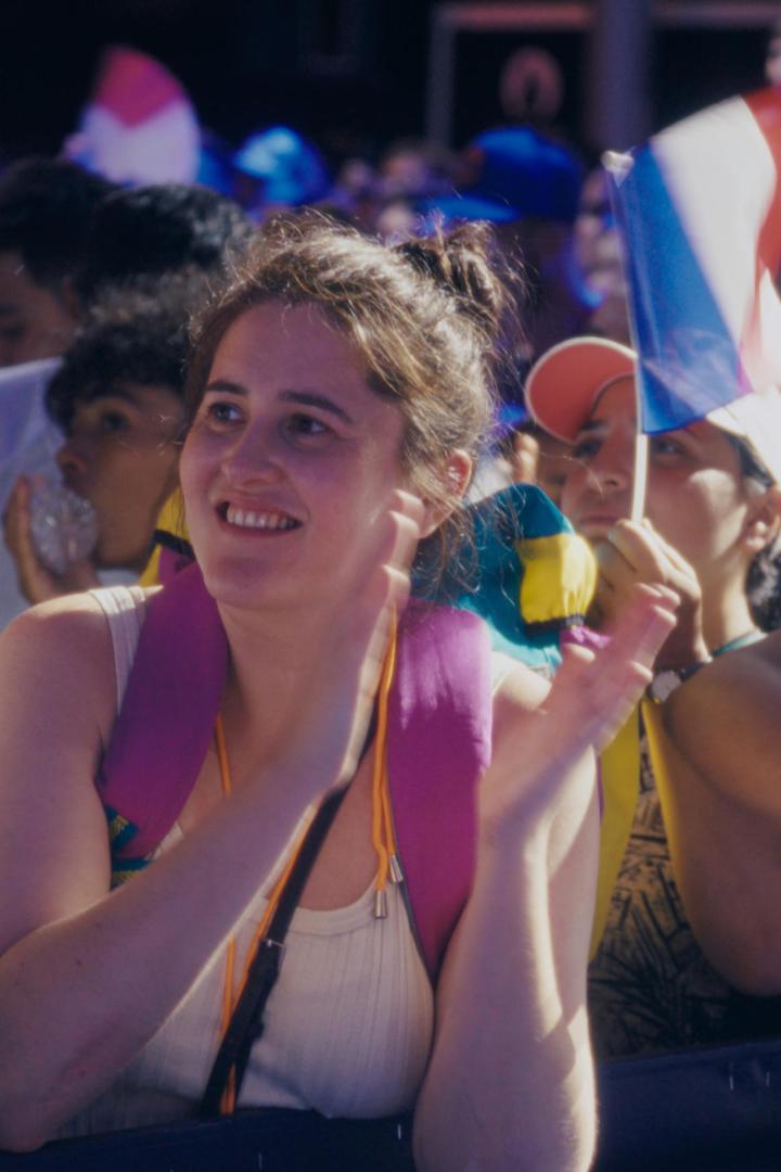 Eine lächelnde Frau klatscht inmitten einer Menschenmenge mit französischen Flaggen.