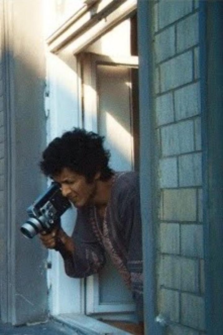 Ein Mann filmt mit einer alten Super-8-Kamera aus einem Fenster.