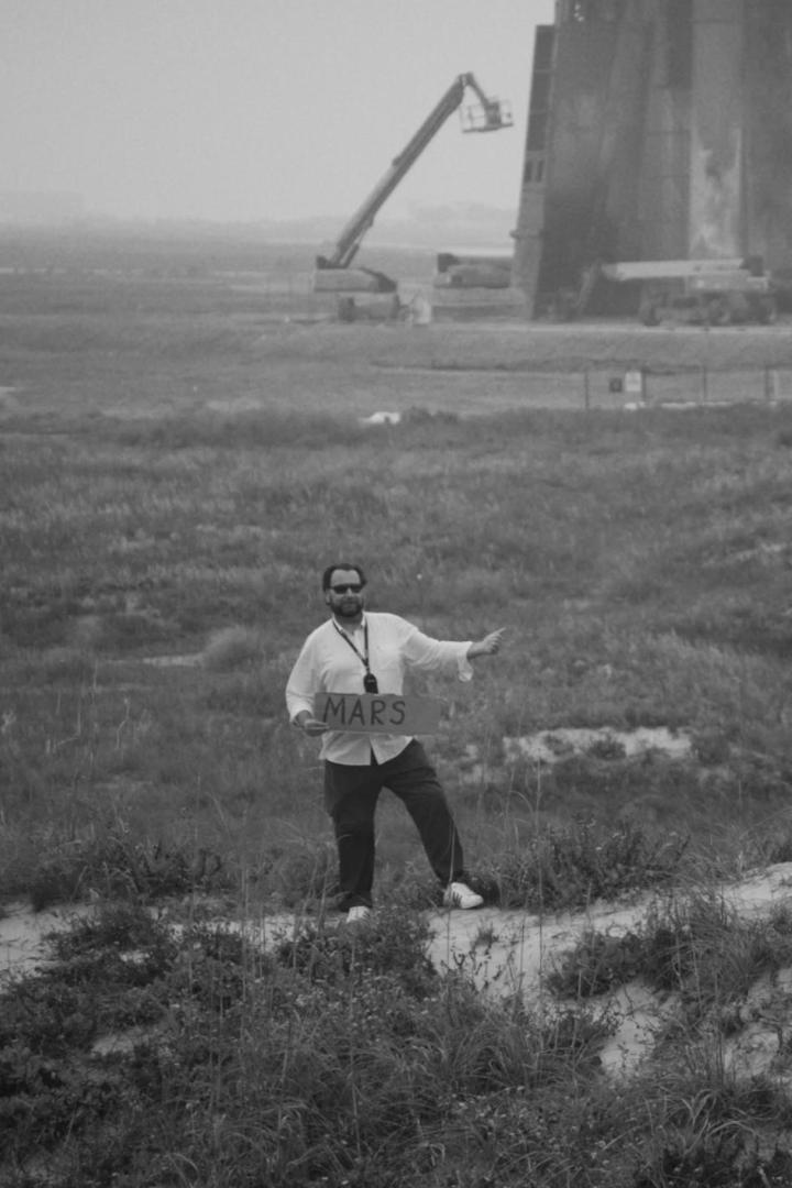 Eine Person steht mit einem „Mars“-Schild vor einer Raketenstartanlage.