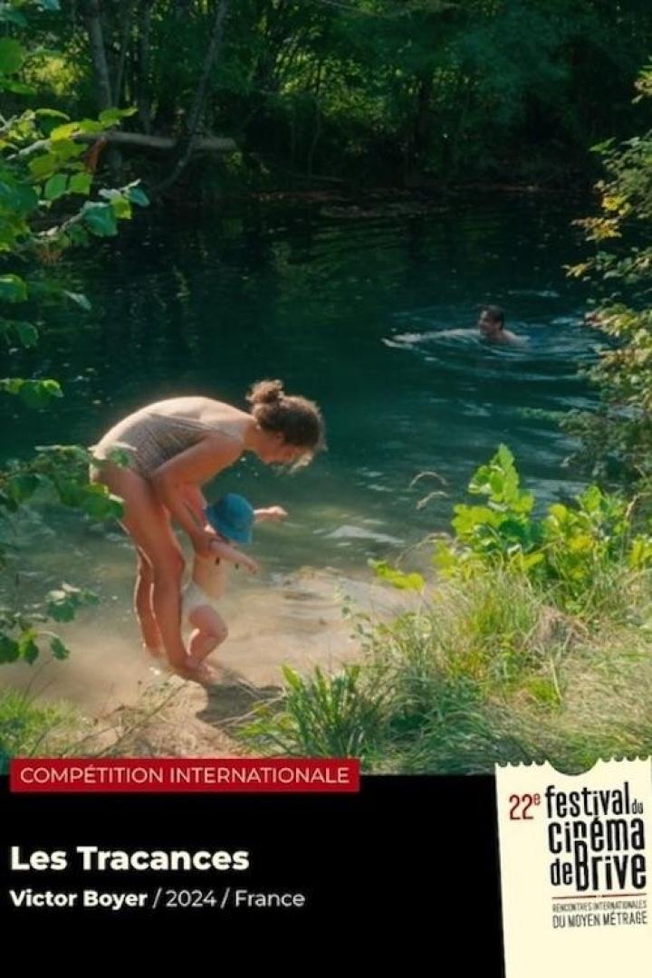 Eine Frau mit Kind am Ufer eines Sees, im Hintergrund schwimmt eine Person.