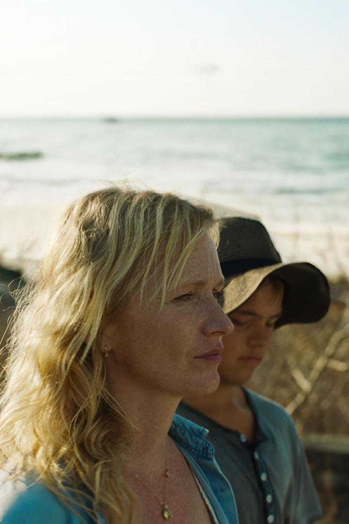 Eine Frau und ein Kind stehen am Strand und schauen in die Ferne.