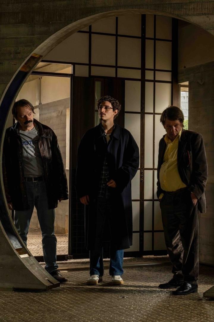 Drei Männer stehen in einem Gebäude mit einem kreisförmigen Eingang.