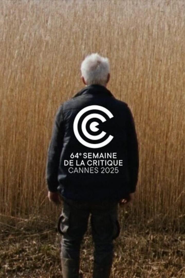 Ein Mann steht vor einem Feld; auf seiner Jacke steht „64e Semaine de la Critique Cannes 2025“.