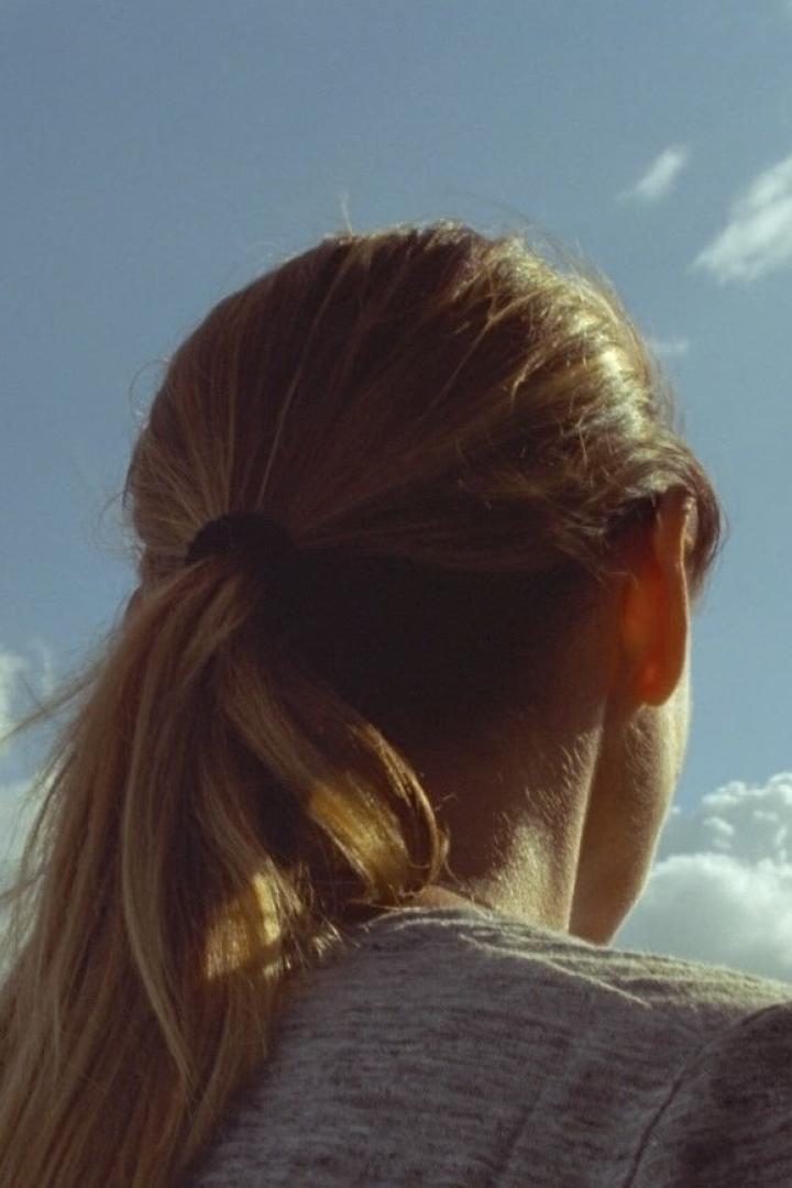 Eine Frau mit blonden Haaren blickt in den blauen Himmel.