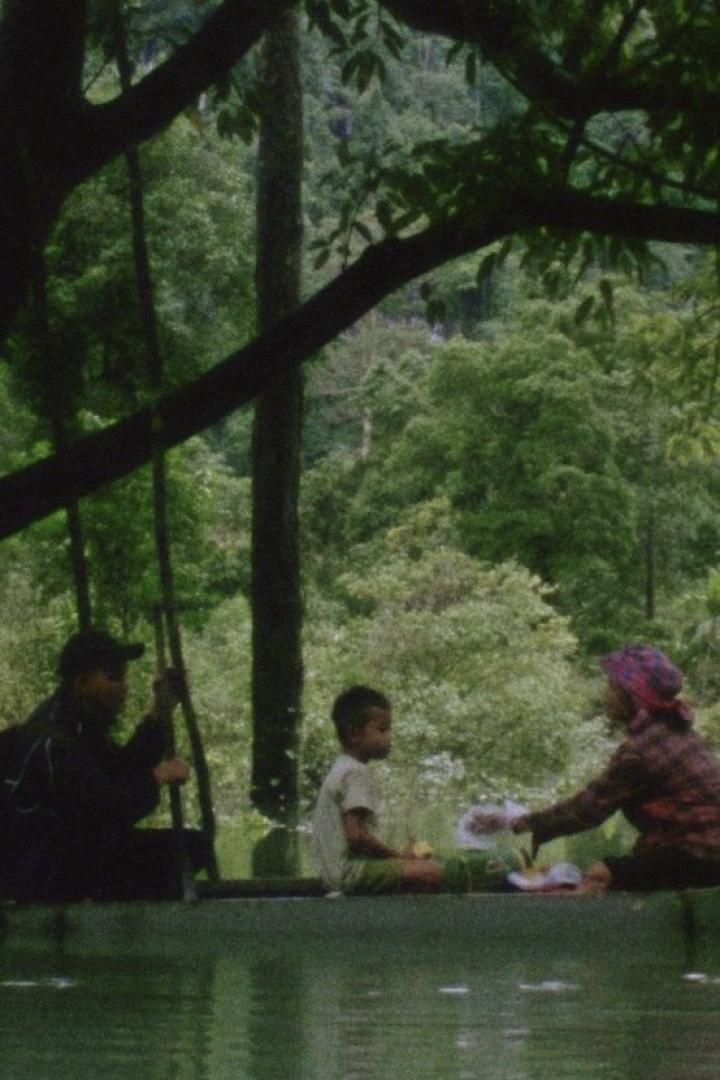 Eine Familie sitzt auf einem Floß auf einem ruhigen Gewässer, umgeben von üppigem Grün.