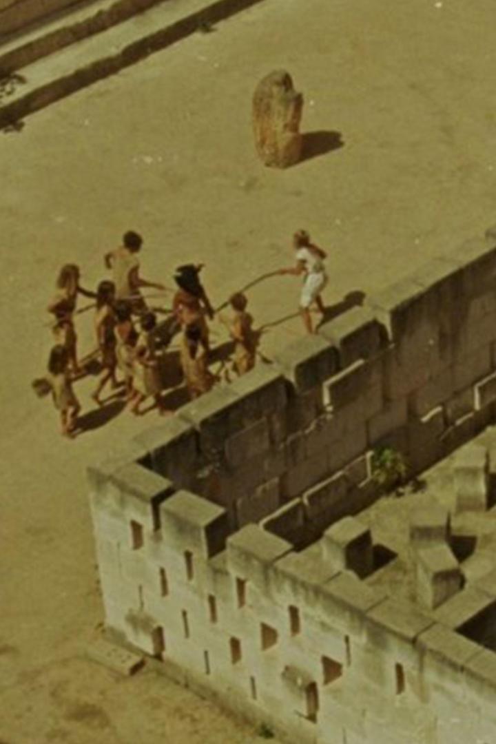 Eine Gruppe von Kindern spielt mit einer Frau in einer alten Festung.
