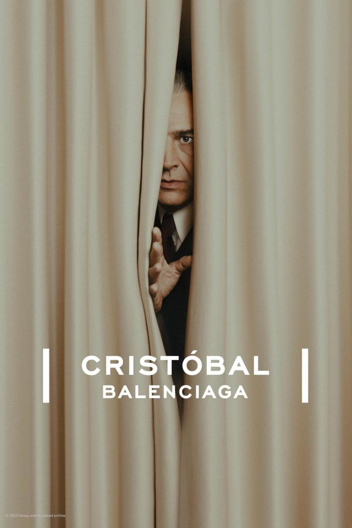 Ein Mann blickt durch einen Vorhang, im Vordergrund der Schriftzug „Cristóbal Balenciaga“.
