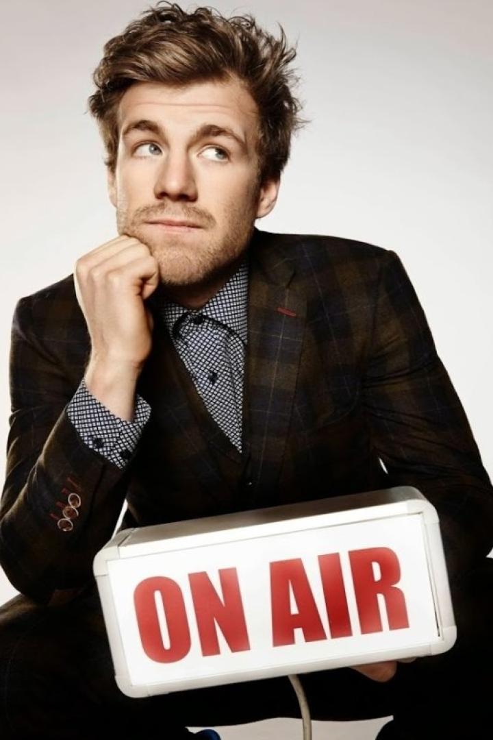 Ein Mann im Anzug hält ein Schild mit der Aufschrift „ON AIR“.