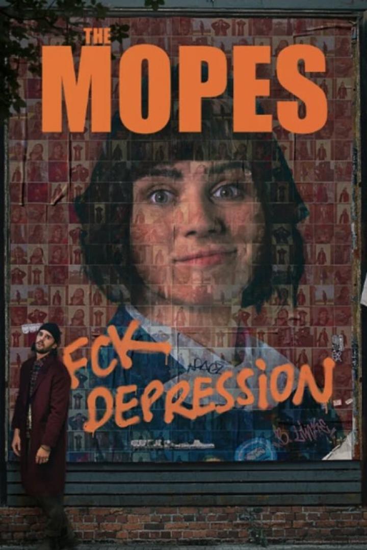 Ein Mann steht vor einem Plakat der Band „The Mopes“ mit dem Slogan „FCK DEPRESSION“.