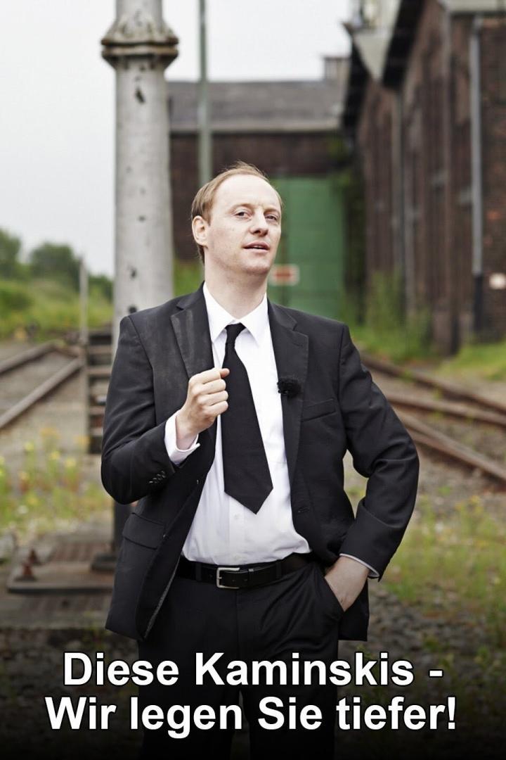 Ein Mann im Anzug steht vor einem alten Bahnhofsgelände.