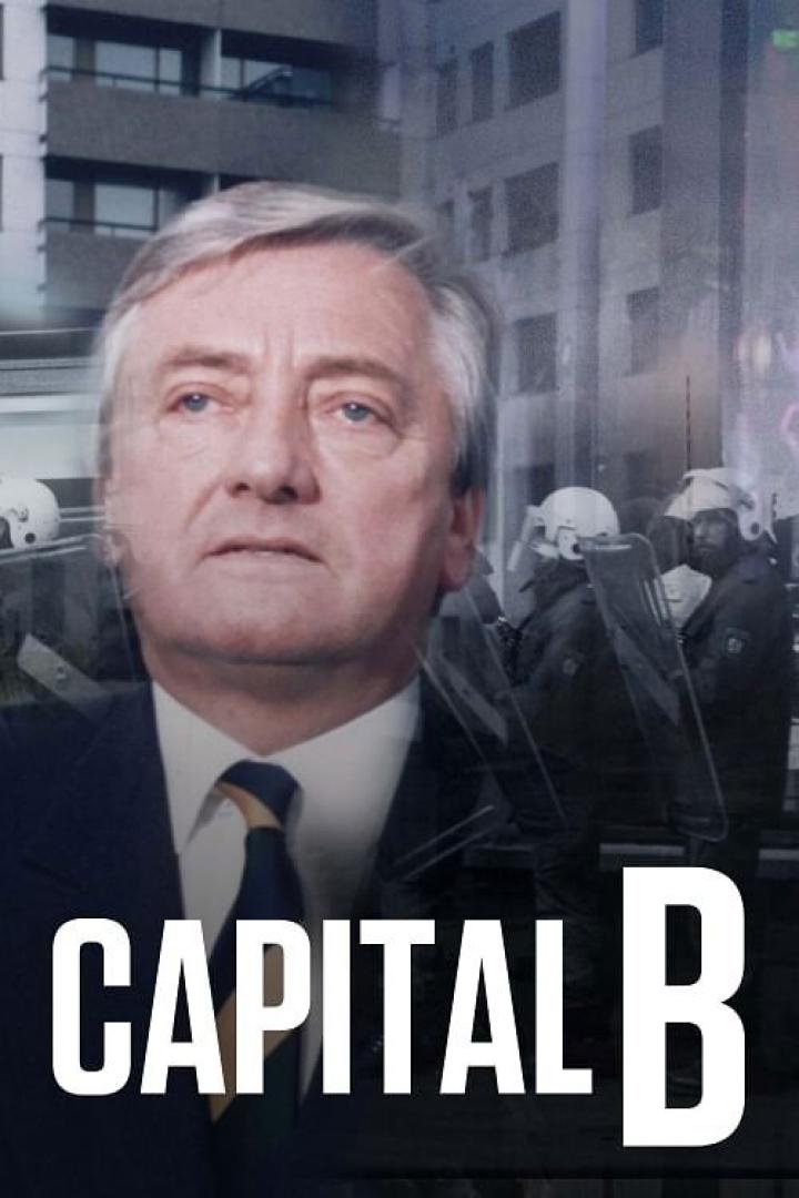 Ein Porträt eines Mannes vor dem Hintergrund einer Demonstration mit Polizisten.