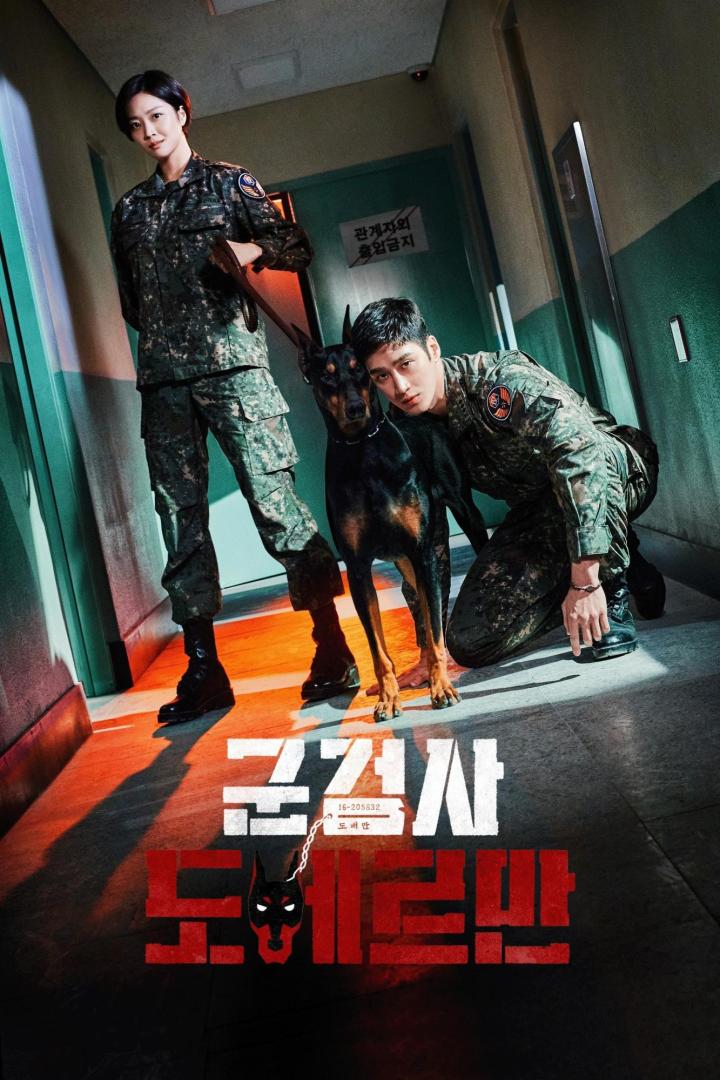 Zwei Militärpolizisten posieren mit einem Dobermann in einem Flur.