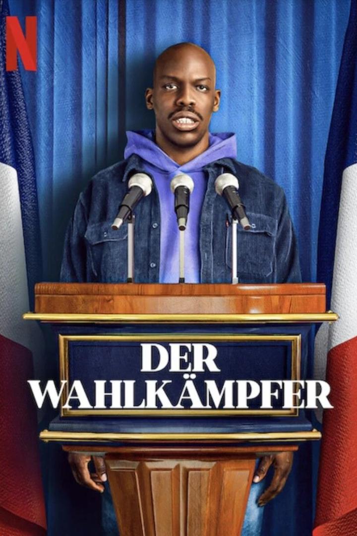 Ein Mann steht am Rednerpult vor einer französischen Flagge für „Der Wahlkämpfer“.