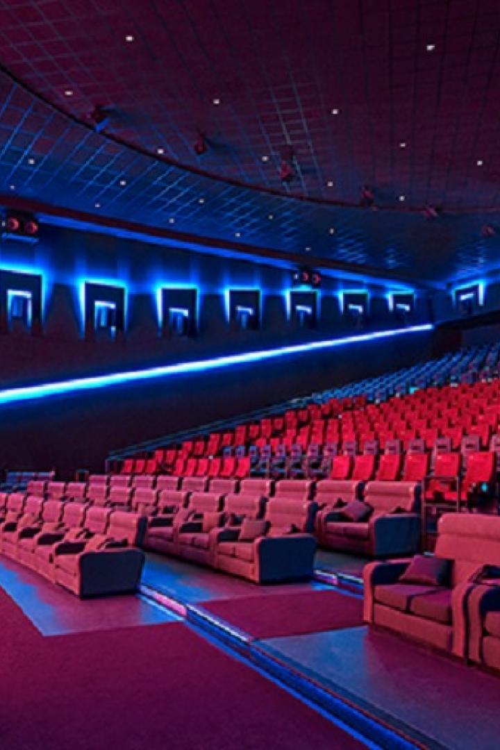 Innenansicht eines Cineplexx-Kinosaals mit roten Sitzen und blauer Beleuchtung.