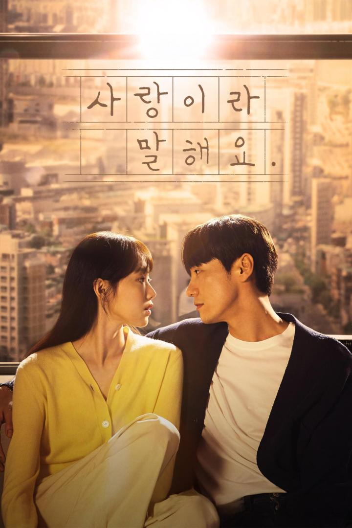 Ein Mann und eine Frau sitzen vor einem Fenster mit Blick auf eine Stadt.