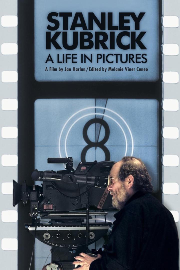 Ein Mann hinter einer Filmkamera vor dem Hintergrund des Filmplakats „Stanley Kubrick: A Life in Pictures“.