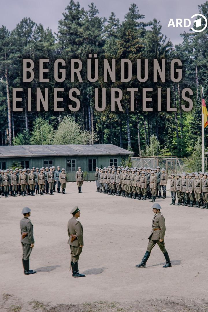 Soldaten in Uniform stehen auf einem Exerzierplatz vor Baracken und einer Deutschlandflagge.