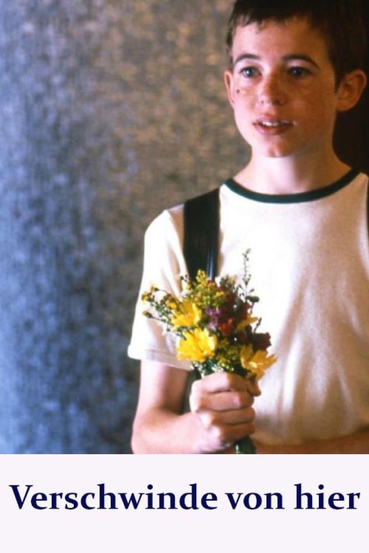 Ein junger Mann mit Sommersprossen hält einen bunten Blumenstrauß.