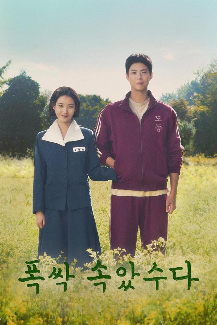 Ein Mann und eine Frau in Schuluniform stehen in einem Feld mit Blumen.