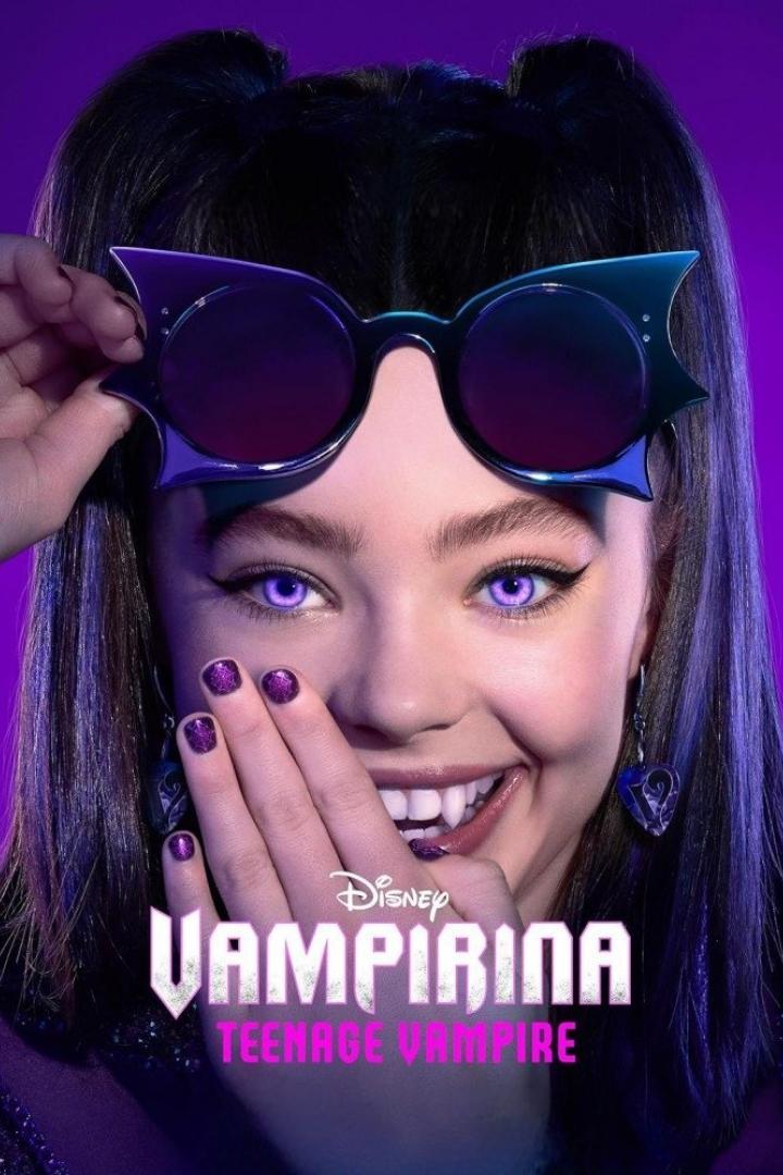 Ein junges Mädchen mit lila Augen und Vampirzähnen lächelt und trägt eine ausgefallene Sonnenbrille.