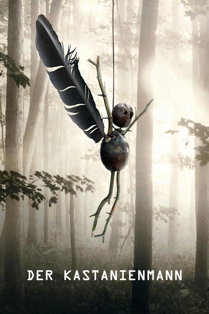 Ein Kastanienmann hängt vor einem nebligen Wald.