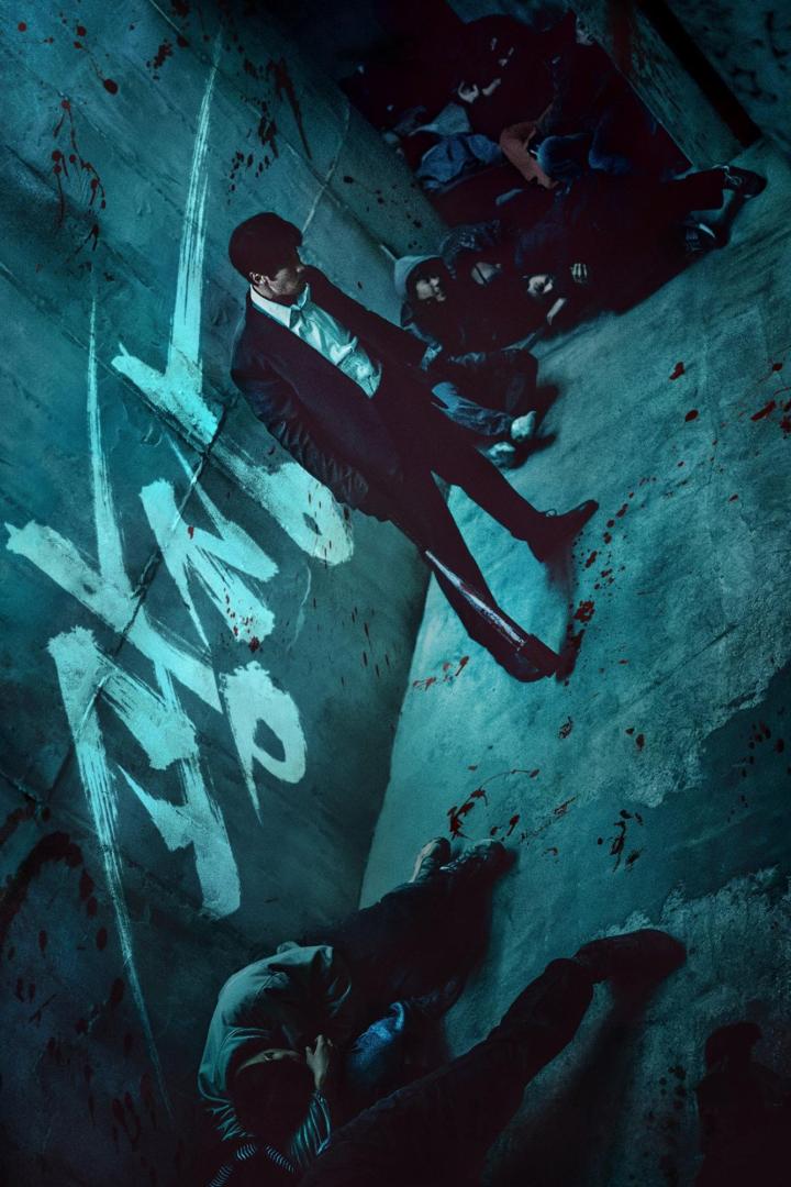 Ein Mann im Anzug steht in einem blutbefleckten Raum mit Graffiti an der Wand.