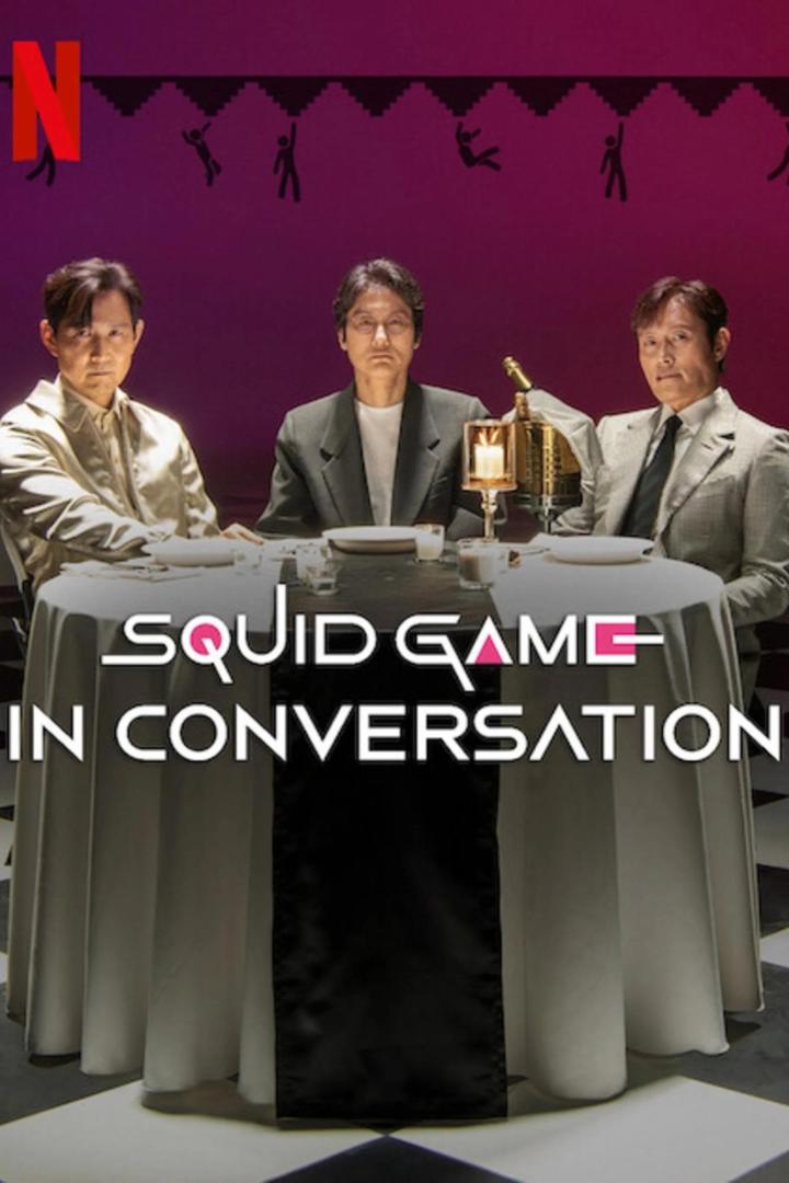 Drei Männer sitzen an einem Tisch im Stil von „Squid Game“ für ein Gespräch.