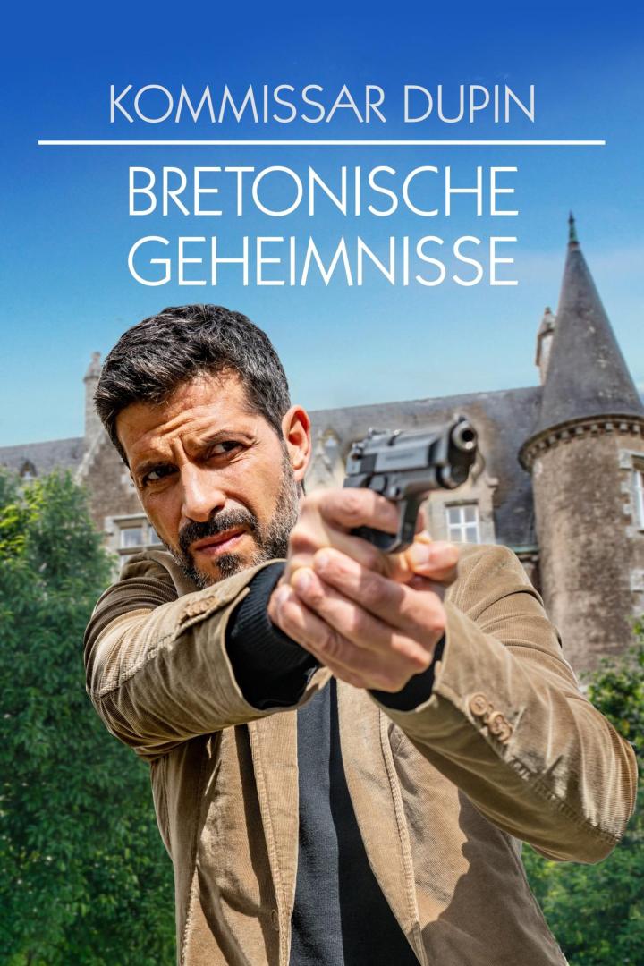 Ein Mann, Kommissar Dupin, zielt mit einer Pistole vor einem Schloss im Film „Bretonische Geheimnisse“.