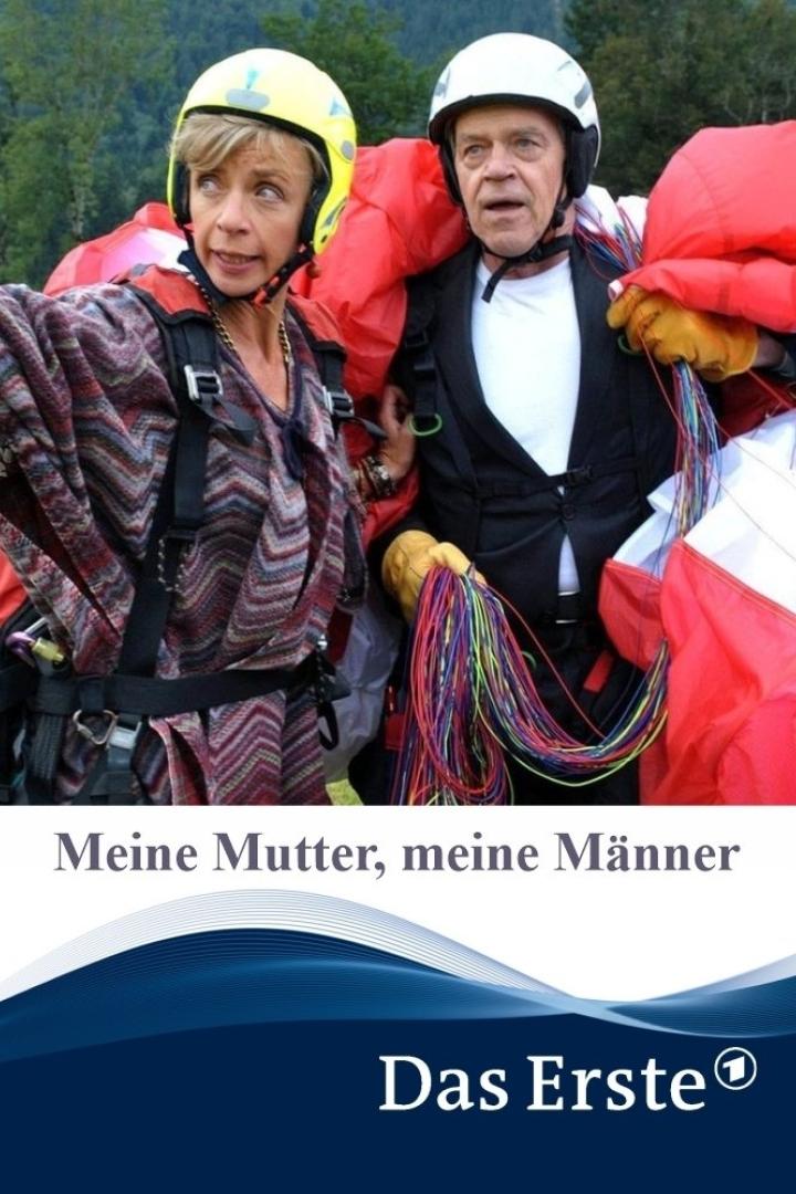 Zwei Personen mit Helmen und Fallschirmen vor einer Bergkulisse.