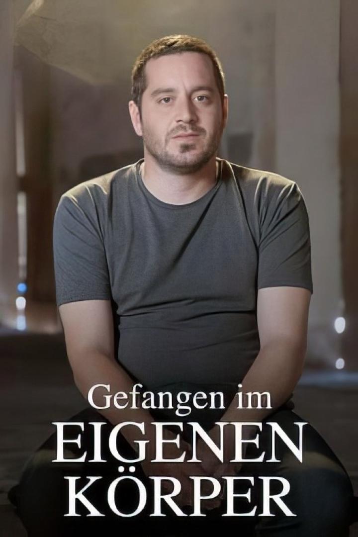 Ein Mann vor dem Titelbild von „Gefangen im eigenen Körper“.