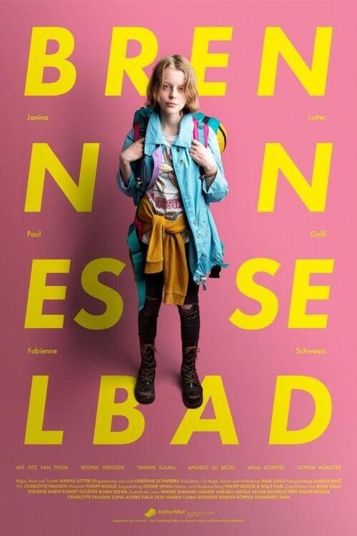 Das Filmplakat zu „Brennen sollst du“. Eine junge Frau steht vor einem pinkfarbenen Hintergrund mit gelben Buchstaben.
