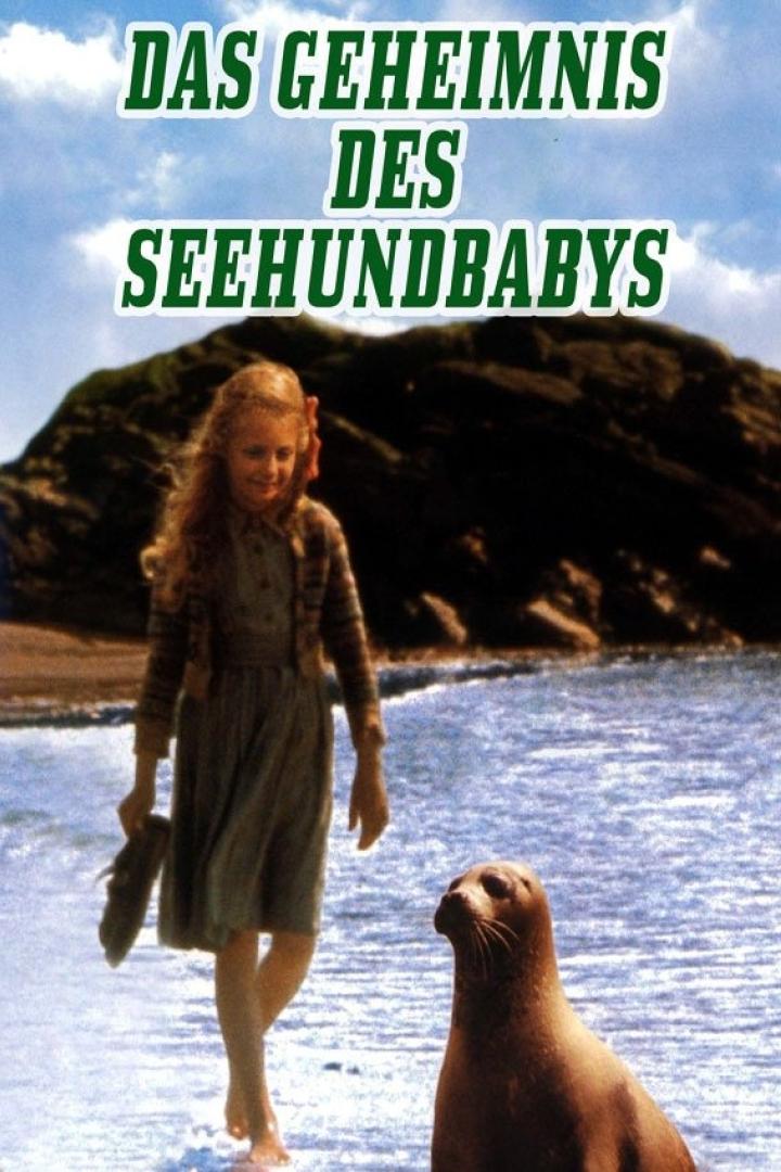 Eine junge Frau steht am Strand vor einem Seehund; Filmposter „Das Geheimnis des Seehundbabys“.