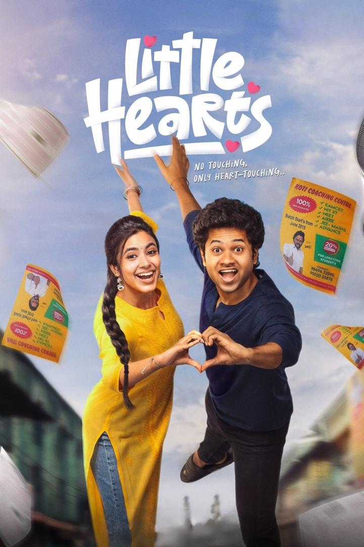 Ein Mann und eine Frau formen mit ihren Händen ein Herz vor dem Filmposter „Little Hearts“.